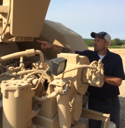 Man pointing at a bank of grease fittings.